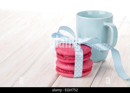 Roten Macarons mit blauen Band und Milchschale auf weißer Holztisch Stockfoto