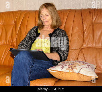 Ältere Dame mit einem Tabletcomputer sitzen. Stockfoto