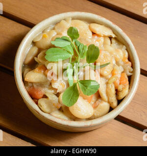 Pikante spanische Bohnen-Eintopf mit Gemüse in einer Schüssel braun Terra Cotta. Fabada Asturiana. Stockfoto