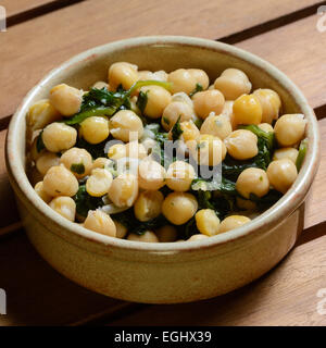 Tapas. Kichererbsen & Spinat gekocht eine würzige vorrätig, serviert in einer braunen Keramikschüssel auf einer hölzernen Tischplatte Stockfoto