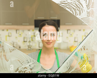 junge schöne Hausfrau waschen Fenster zu Hause Stockfoto