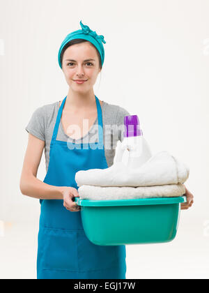 glücklich Putzfrau hält Becken mit saubere Handtücher und Reinigungsmittel, isoliert auf weißem Hintergrund Stockfoto