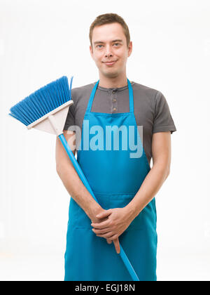 junge Kaukasischen Männchen halten Besen, stehend vor weißem Hintergrund Stockfoto