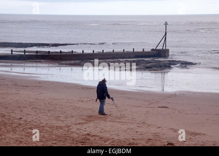 Ein Mann verwendet einen Metalldetektor am Strand von Exmouth Stockfoto