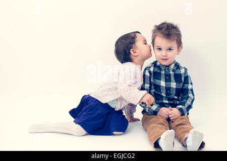 kleines Mädchen küssen ihr älteren Bruder auf die Wange, isoliert Stockfoto