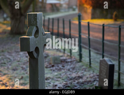 Frost bedeckt Grabsteine auf einem Friedhof in einem Dorf in Herefordshire, England, am frühen Morgen des gefrorenen Wintermorgen. Stockfoto