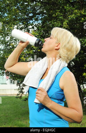 Eine Frau trinken Senior mit Wasserflasche und Handtuch Sport treiben Stockfoto