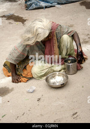 Alten Indianerin Hilfesuchenden auf einer viel befahrenen Straße OnJuly 28,2013 in Hyderabad, AP, Indien. Stockfoto