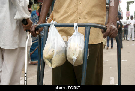 Alten behinderten Mann tragen Nahrung gebunden, die Krücke in einer belebten Straße am Juli 28,2013 in Hyderabad, AP, Indien. Stockfoto