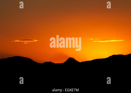 Die Sonne hinter einer Bergkette im Süden Islands, die Berge, die Schatten im Dunst. Stockfoto