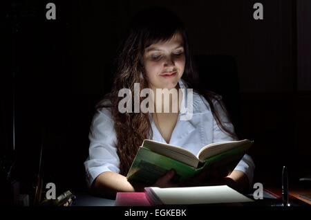 Eine junge Wissenschaftlerin mit einem Buch in der Dunkelheit Stockfoto