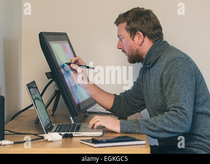 Kreative Mann am Schreibtisch mit Touch-Screen-Tablette Stockfoto