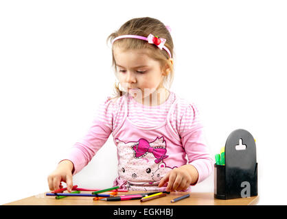 kleines Mädchen ist zeichnen mit Farbstiften beim Sitzen am Tisch Stockfoto