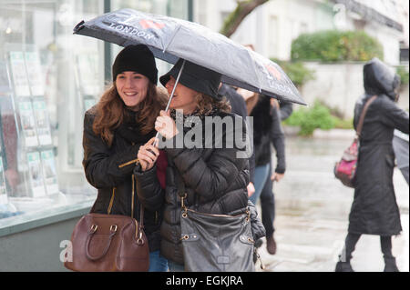 Zwei Damen eine Straße hinunter, während Zuflucht vor dem Regen unter einem Regenschirm in Notting Hill, London. Stockfoto