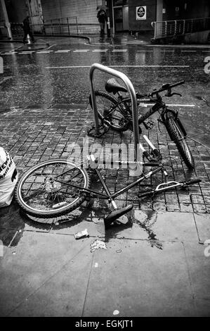 Schwarz-weiß Bild von zwei Fahrräder gesichert zu einem Fahrradständer, eine vandalized liegen in Manchester Street 2015 Stockfoto