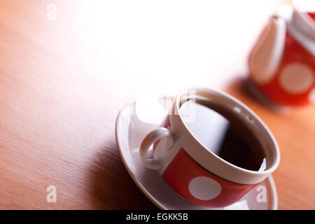 Tasse schwarzer Tee hautnah auf einem Tisch mit Teekanne auf Hintergrund unscharf Stockfoto