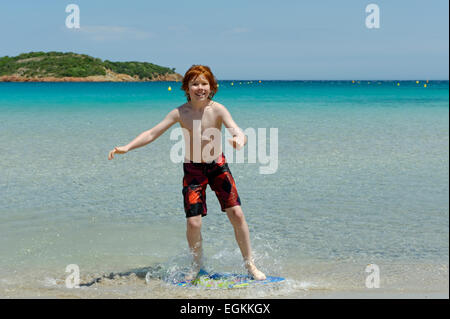 Junge mit seinem Surfbrett, Strand Board oder Skimboarden Surfen, am Strand, Bucht von Rondinara, Südostküste, Korsika, Frankreich Stockfoto