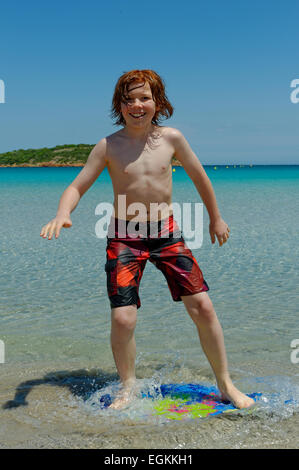 Junge mit seinem Surfbrett, Strand Board oder Skimboarden Surfen, am Strand, Bucht von Rondinara, Südostküste, Korsika, Frankreich Stockfoto