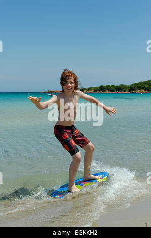 Junge mit seinem Surfbrett, Strand Board oder Skimboarden Surfen, am Strand, Bucht von Rondinara, Südostküste, Korsika, Frankreich Stockfoto