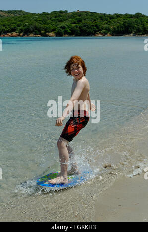 Junge mit seinem Surfbrett, Strand Board oder Skimboarden Surfen, am Strand, Bucht von Rondinara, Südostküste, Korsika, Frankreich Stockfoto