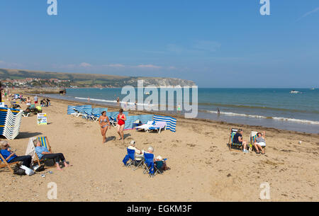 Touristen am Swanage Beach Dorset England Großbritannien im Sommer mit blauem Himmelsmeer mit Wellen an der Jurassic Coast Stockfoto