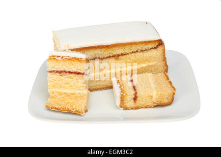 Geeiste Madeira-Kuchen mit geschnittenen Scheiben auf einem Teller isoliert gegen weiß Stockfoto