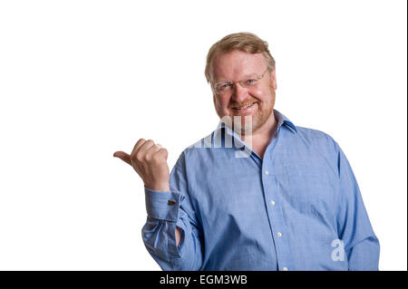 Freundlicher mittleren Alter bärtiger Mann im blauen Hemd zeigt mit Daumen - auf weiß Stockfoto