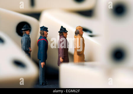 Eine Reihe von Miniaturfiguren Skala Modell stehen in einer Linie unter einem Haufen von Domino. Stockfoto