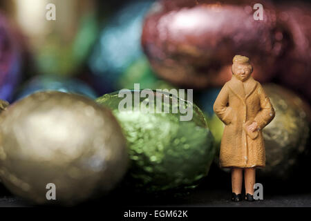 Eine Miniatur-Skala Modell Figur stehen unter einem Haufen von bunt und glänzend Mini Ostereier. Stockfoto