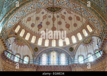 Blaue Moschee Sultan-Ahmed-Moschee Gebetshalle Innenraum Istanbul Türkei | ISTANBUL, Türkei — Der kunstvolle Innenraum der Sultan-Ahmed-Moschee, allgemein bekannt als die Blaue Moschee, ist mit mehr als 21.000 handgefertigten İznik- und Kütahya-Keramikfliesen geschmückt, deren überwiegend blaue und grüne Farbtöne der Moschee ihren populären Namen verleihen. Offiziell Sultanahmet Camii auf Türkisch genannt, wurde sie von Sultan Ahmed I. in Auftrag gegeben und von 1609 bis 1616 unter dem Chefarchitekten Sedefkâr Mehmed Ağa erbaut. Die übereinander gestapelten Kuppeln und reich verzierten Oberflächen des Gebetssaals — einschließlich Koran-Kalligrafie des Meisterkalligraphen Stockfoto