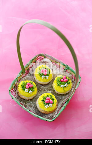 Oster-Cupcakes. Engel Essen Cupcakes mit Vanille Eis und Süßigkeiten Eiern. Stockfoto