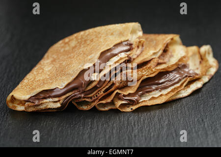 dünne Crepes oder Blinis mit Schokoladencreme auf Schiefer Stockfoto