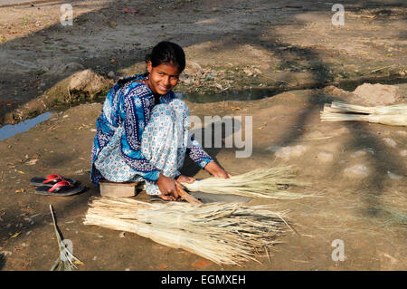 Indische Frau sitzen auf dem Boden machen traditionelle Rasen Reed Bürsten Rajasthan Indien Stockfoto