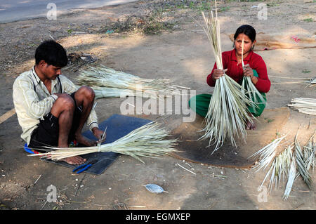 Indischer Mann und Frau sitzen auf dem Boden machen traditionelle Rasen Reed Bürsten Rajasthan Indien Stockfoto