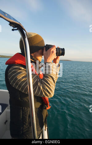 Junger Mann mit dem Fotografieren auf einer Bootstour in Scapa Flow, Orkney Inseln, Schottland. Stockfoto