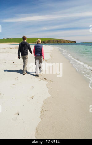 Junge Frau und Mann zu Fuß an einem schönen Sandstrand im Sommersonnenschein, Dingieshowe, Deerness, Orkney Inseln, Schottland. Stockfoto