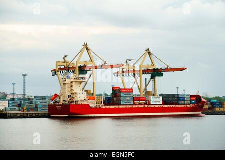 Riga Lettland. Kaufmann Frachtschiffahrt auf Düna Fluss im Freihafen von Riga. Containerschiff Schiff Frederik und dock-Einrichtungen Stockfoto