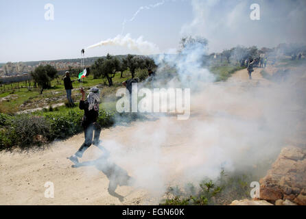 Ramallah. 27. Februar 2015. Ein palästinensischer Demonstrant wirft wieder einen Tränengas abgefeuert von israelischen Soldaten während der Zusammenstöße bei einer wöchentlichen Protest gegen jüdische Siedlungen im Dorf von Bilin, in der Nähe von der Westbank Ramallah am 27. Februar 2015 Kanister. © Fadi Aruri/Xinhua/Alamy Live-Nachrichten Stockfoto