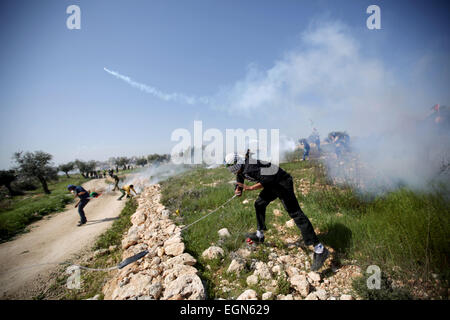 Ramallah. 27. Februar 2015. Ein palästinensischer Demonstrant wirft wieder einen Tränengas abgefeuert von israelischen Soldaten während der Zusammenstöße bei einer wöchentlichen Protest gegen jüdische Siedlungen im Dorf von Bilin, in der Nähe von der Westbank Ramallah am 27. Februar 2015 Kanister. © Fadi Aruri/Xinhua/Alamy Live-Nachrichten Stockfoto