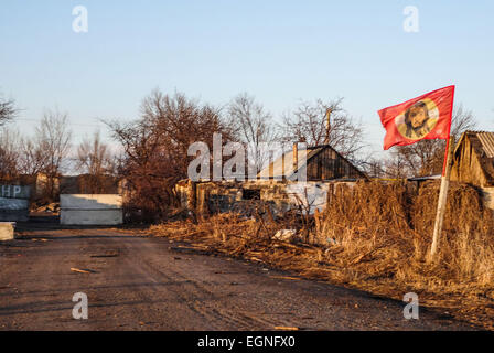 27. Februar 2015 - eine rote Fahne mit dem Bild Christi, flattern in der Straße mit zerstörten Haus im Dorf Nikishino, Donezk, Ukraine. -Dorf Nikishino liegt 20 km von Debalzewe, Ukrainische militärische wurde vor drei Tagen aufgegeben. Separatistischen Kräfte angegriffen es für mehrere Tage. Die letzte Schlacht dauerte mehr als sieben Stunden. Im Dorf gab es kein ganzes Haus. Sogar die Bäume fallen mit Schrapnells. (Kredit-Bild: © ZUMA Draht) Stockfoto