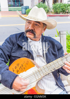 Mexikanische männlichen Gitarrist in weißen Cowboyhut spielen auf einer Bank an der State Street in Santa Barbara, Kalifornien. Stockfoto