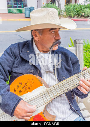 Mexikanische männlichen Gitarrist in weißen Cowboyhut spielen auf einer Bank an der State Street in Santa Barbara, Kalifornien. Stockfoto