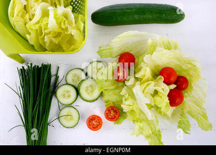 Zubereitung Salat mit Gurken, Salat, Cherry-Tomaten und Schnittlauch auf modernen weißen Holztisch festlegen, über Kopf. Stockfoto