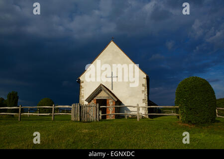 St. Huberts. Sehr dunkle Gewitterwolke Kontrast zu der weißen Kirche. Kirche im Feld Idsworth. Stockfoto