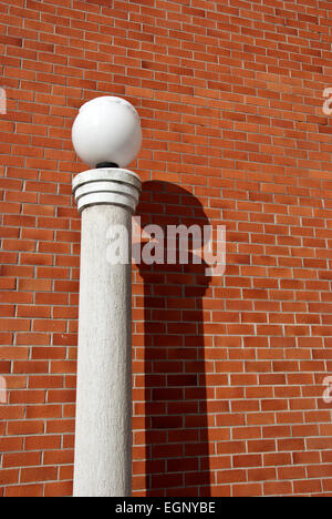 moderne Lampe mit Schnee auf Spalte in der Nähe von roten Backsteinmauer