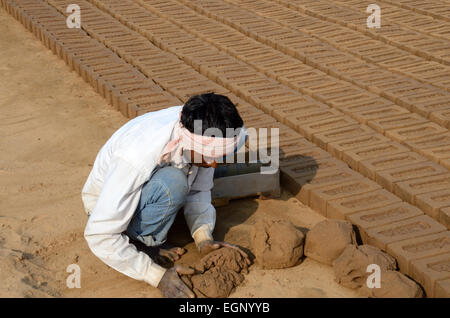 Indischer Mann hocken auf dem Boden, die die Hand gemacht Ziegel aus Ton Schlamm Madhya Pradesh, Indien Stockfoto