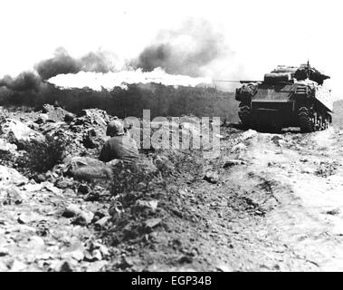 Schlacht von IWO JIMA Februar / März 1945. US-Flammenwerfer ausgerüstet Panzer in Aktion beobachtet von hockend Marines. Stockfoto