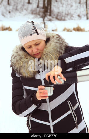 Frau, Gießen heißen Tee aus der Thermoskanne im verschneiten winter Stockfoto