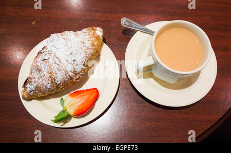 Nachmittagstee im Landhaus eine Tasse Tee und einem frisch gebackenen Mandel-Croissant Stockfoto