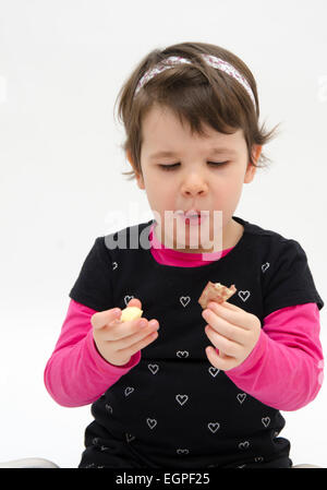 Entzückende kleine Mädchen essen ein Stück Apfel isoliert auf weißem Hintergrund Stockfoto